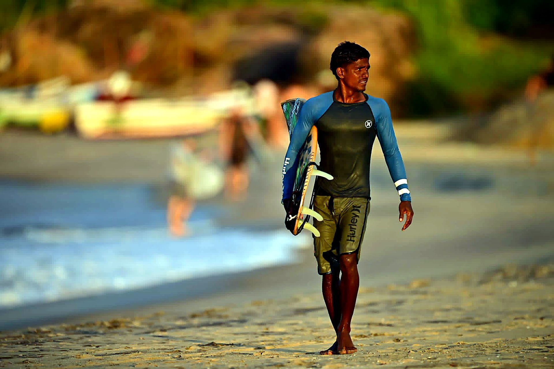 Surfer walking the beach with a board at dawn