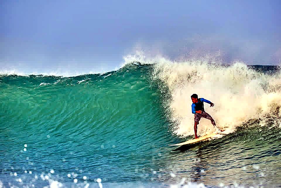 Surfer riding a clean green wave at Arugam Bay